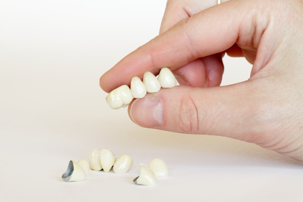 A person's hand holding a small piece of a tooth.
	